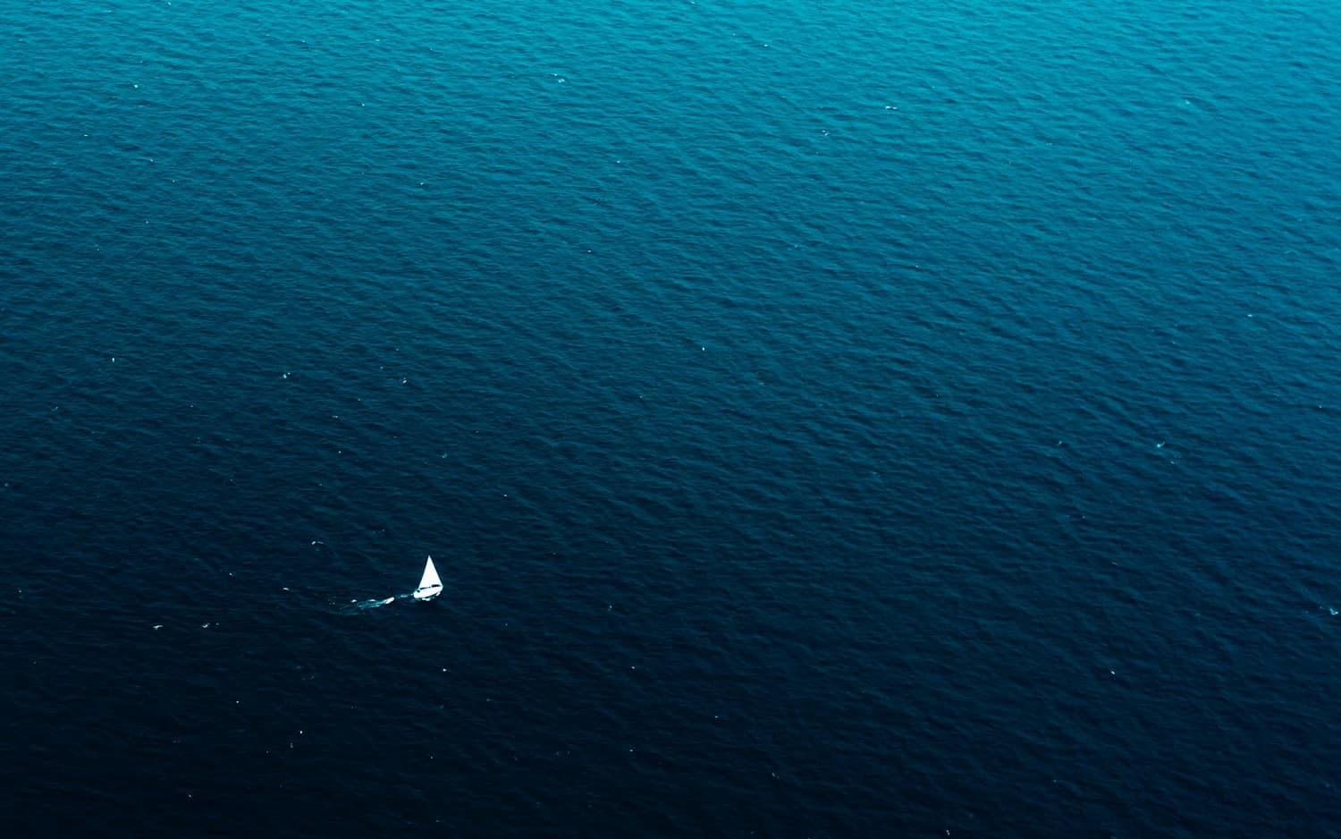 A sailing yacht viewed from above on blue open water